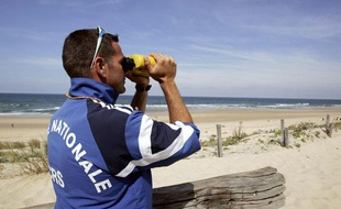 Un maître-nageur sauveteur de la police nationale observe la côte aquitaine à la jumelle le 2 août 2007 sur la plage du Porge près de Lacanau.