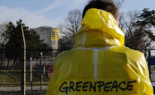 Un militant de Greenpeace mardi 18 mars à Fessenheim regarde le réacteur de la centrale sur lequel a été déployée une banderole par le groupe écologiste protestant contre l'insécurité des vieilles centrales nucléaires