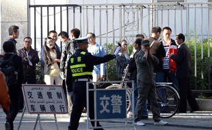 Un policier chinois contrôle la foule devant l'entrée du tribunal d'Urumqi, capitale du Xinjiang, où l'intellectuel ouïghour Ilham Tohti est jugé, le 17 septembre 2014