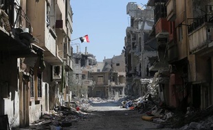 Le drapeau syrien flotte au balcon dans une rue dévastée de Homs, en Syrie, le 31 juillet 2013.