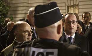 Le ministre de l'Intérieur Bernard Cazeneuve et le président François Hollande avec un officier de police, le 31 décembre 2015 à Paris.