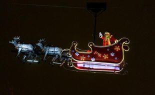 Un homme déguisé en Père Noël salue la foule depuis son traineau sur les Champs Elysées à Paris le 23 décembre 2014