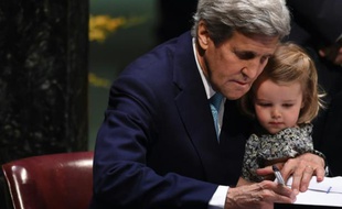 Le secrétaire d'Etat américain John Kerry signe l'accord sur le climat, tenant sa petite-fille, le 22 avril 2016 à l'ONU à New York