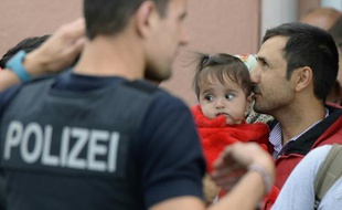 Un réfugié tient son enfant dans ses bras et attend un train spécial à la gare de Freilassing, près de la frontière autrichienne, le 15 septembre 2015