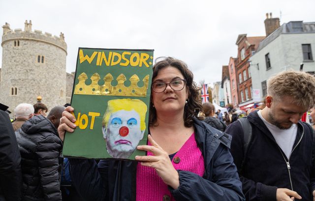 Pendant ce temps à quelques mètres de là, des manifestants se rassemblent devant le château de Windsor. Sur ce panneau, on peut déchiffrer « Windsor = crown, not clown » (Windsor = couronne, pas clown), avec les dessins qui vont bien.