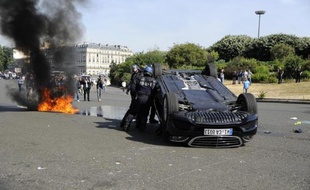 Une voiture renversée alors que des taxis bloquent le passage Porte Maillot à Paris, le 25 juin 2015