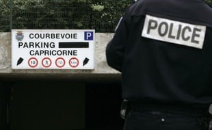 Un policier se tient devant le parking dans lequel a eu lieu l'agression mortelle de Brahim Deby, le 2 juillet 2007, à Courbevoie (Hauts-de-Seine).