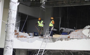 Des secouristes travaillent dans le bâtiment éventré de l'ONU quelques heures après l'attaque à la voiture piégée qui a tué au moins 18 personnes, vendredi 26 août à Abuja (Nigéria)
