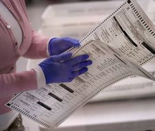 An election worker carries two ballots to be verified inside the Maricopa County Recorders Office, Thursday, Nov. 10, 2022, in Phoenix. (AP Photo/Matt York)/AZMY101/22314646069850//2211101901