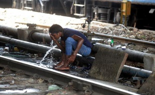 Un Indien se rafraîchit près d'une voie ferrée à New Delhi le 27 juin 2014