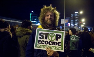 Un protestataire, pendant la COP25 à Madrid, tient une pancarte dans la main mentionnant « Stop à l'écocide, changez la loi »