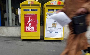 Une personne marche devant des boites aux lettres près d'un point de vote installé devant un bureau de poste dans le cadre de la "votation citoyenne" sur l'avenir de la Poste, le 3 octobre 2009, à Paris.