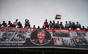 Des manifestants soudanais scandent des slogans en brandissant des drapeaux nationaux soudanais lors d'une manifestation devant le complexe militaire de Khartoum, dans la capitale, le 20 avril 2019.