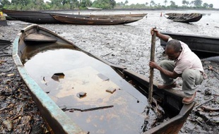 Un habitant de la communauté de Bodo, au sud du Nigeria, tente de séparer avec un bâton le pétrole de l'eau, le 11 août 2011 après une pollution provoquée par la compagnie Shell dans le Delta du Niger