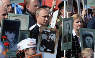 Le président russe Vladimir Poutine brandit, comme de nombreux autres participants, une photo de son père lors du cortège célébrant les 70 ans de la victoire sur Hitler