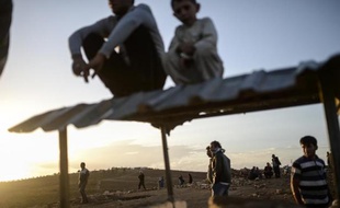 Des Kurdes observent les combats entre jihadistes de l'EI et des combattants kurdes, le 28 septembre 2014 à la frontière avec la Syrie