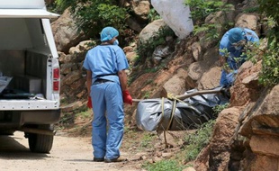 Des experts scientifiques portent le corps d'une des dix victimes trouvées dans des tombes clandestines dans la ville d'Acapulco, le 22 juin 2015