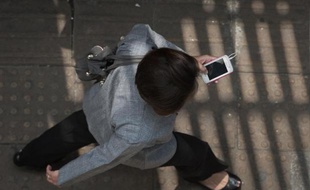 Une femme utilise son smartphone tout en marchant dans une rue
