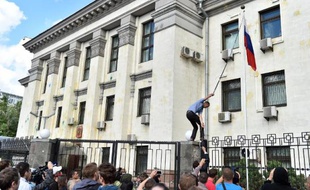 Un homme décroche le drapeau russe de l'ambassade de Russie à Kiev en Ukraine, lors d'une manifestation anti-Russes, le 14 juin 2014
