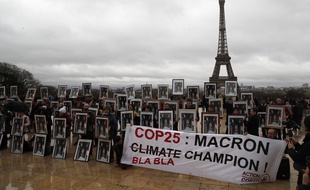 Une centaine de militants tiennent des portraits du président Emmanuel Macron pour exhorter la France à agir lors des négociations sur le climat de la COP 25 de l'ONU à Madrid, lors d'un rassemblement place du Trocadéro face à la Tour Eiffel à Paris, dimanche 8 décembre 2019.