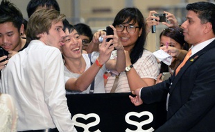 La star des "Youtubers", le Suédois Felix Kjellberg, alias PewDiePie (G), pose pour un selfie avec un de ses fans, à Singapour, le 23 mai 2013