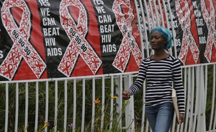 Illustration d'une femme marchant devant des affiches pour la Journée internationale de lutte contre le sida le 1er décembre 2017 à Johannesbourg en Afrique du Sud.