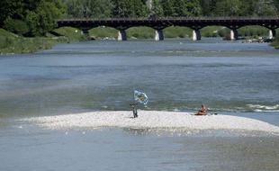 Un homme profite du soleil sur une ile au beau milieu de la rivière Isar dans les environs de Munich (Photo illustration).