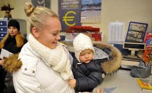 Une Lettone tient en main un sachet dans lequel se trouve des pièces de monnaie en euro, le 10 décembre 2013 à Riga