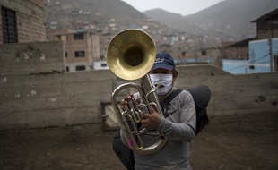 Un musicien joue du tuba en portant un masque avec un zip, à Lima, au Pérou, le 17 juillet