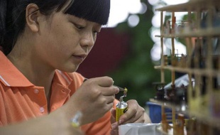 Une employée fabriquant un immeuble miniature dans l'usine Canyon Models à Shenzhen le 23 avril 2015