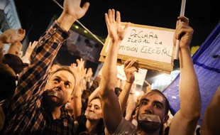 Des Espagnols portent du scotch sur la bouche lors d'une manifestation contre la crise économique et le chômage à la Puerta del Sol, à Madrid, le 20 mai 2011.
