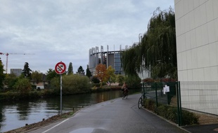 Au bord de l'eau, la piste cyclable qui va bientôt comporter de nouvelles grilles se trouve derrière un des bâtiments du Parlement, lui-même situé derrière le conseil de l'Europe.