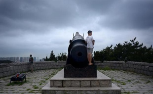 Un jeune homme se tient derrière un canon alors qu'il visite un fort contruit par les Allemands pendant le Première guerre mondiale à Qingdao (Chine)
