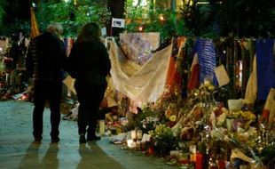 Des passants, le 31 décembre 2015, lisant les hommages aux victimes déposés sur le trottoir en face de la salle de concert "le Bataclan", lieu de l'une des attaques du 13 novembre 2015 à Paris