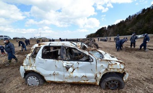 Des officiers de police cherchent les restes des personnes disparues à Namie, près de la centrale nucléaire accidentée de Fukushima, le 11 mars 2015