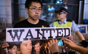 Un homme montre une affiche avec les photos des moliciers accusés d'avoir battu un manifestant, le 15 octobre 2014 à Hong Kong