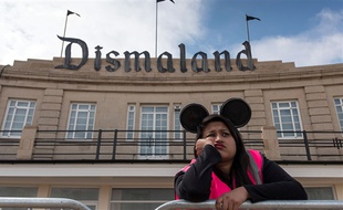 Une employée à l'entrée de Dismaland, le parc d'attractions de Banksy qui parodie Disney