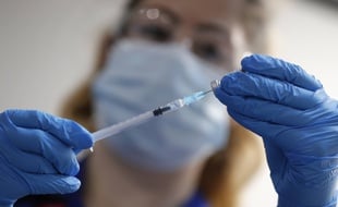 Illustration d'une infirmière préparant une injection du vaccin Pfizer.