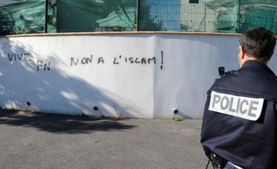 Un policier devant un graffiti sur un mur"Vice FN, non à l'Islam" à proximité de la mosquée de Béziers, le 8 octobre 2015