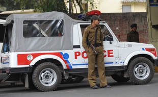 Un agent se tient devant une voiture de police, à New Delhi, le 4 février 2012.