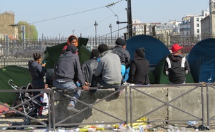 Des réfugiés aux abords de leurs tentes de fortune sous un pont de la ligne 2 du métro parisien à deux pas de la station Porte de la Chapelle.