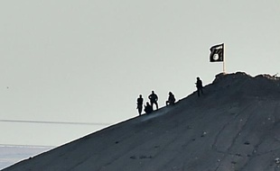 Des jihadistes du groupe Etat Islamique plantent le drapeau de l'EI sur une colline de Kobane, le 6 octobre 2014 en Syrie