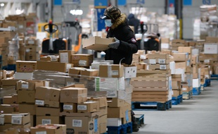 Un manutentionnaire portant un masque dans une plateforme logistique de grande surface.