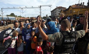 Des migrants face à un policier macédonien, dans la gare ferroviaire de Gevgelija dans le sud de la Macédoine, le 19 août 2015.