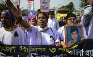 Des ouvriers du textile et des survivants du Rana Plaza défilent aux abords du lieu de la catastrophe qui a fait plus de 1.100 morts en 2013, le 24 avril 2016 à Savar dans la banlieue de Dacca