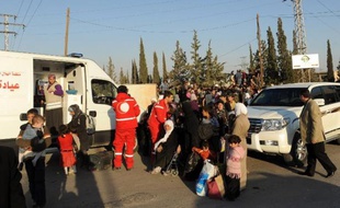 Des membres du Croissant rouge syrien évacuent des femmes et des enfants dans une banlieue de Damas, le 12 octobre 2013