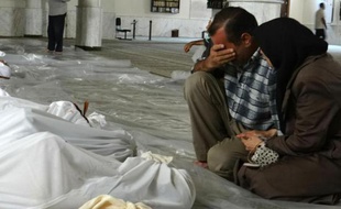 Photo fournie par le réseau d'opposition syrienne Shaam News montrant un couple pleurant face aux cadavres de proches, tués lors d'une attaque qui pourrait être d'origine chimique, le 21 août 2013 près de Damas