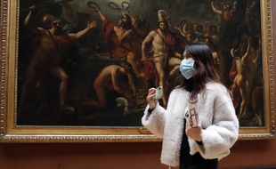 Une touriste, portant un masque, visite le musée du Louvre à Paris, jeudi 5 mars.