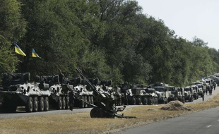 Ukrainian soldiers park their hardware on the roadside as they wait for the start of the march into the town of Mariupol, eastern Ukraine, Wednesday, Aug. 27, 2014. Pro-Russian rebel forces entered a key town of Novoazovsk in southeastern Ukraine on Wednesday after three days of heavy shelling, the town's mayor said, capturing new territory far from most of their battles with government troops.(AP Photo/Sergei Grits)/XSG118/791886667321/PHOTO SHOT THROUGH VEHICLE WINDOW/1408271819