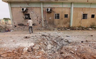Un journaliste regarde le bâtiment endommagé d'un camp d'une brigade islamiste le 28 mai 2014 à Benghazi, en Libye